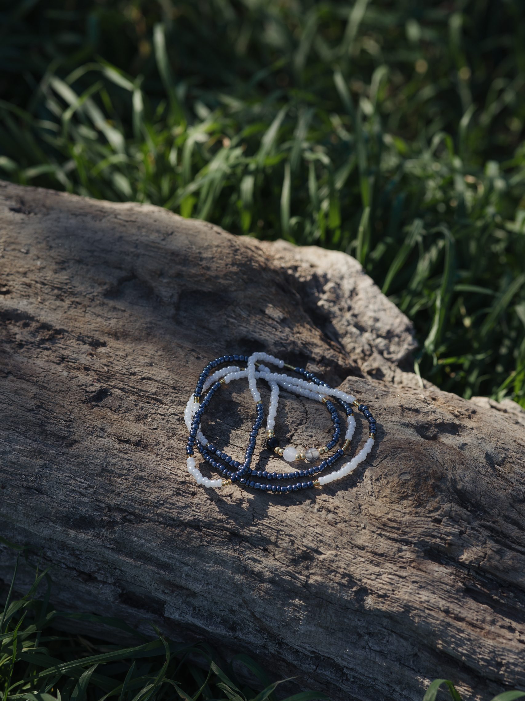 Baya bin bin élastique Soléia Tria en perles de verre gris foncé anthracite metallisées irisées nacré et perles de verre blanches et dorées japonaises miyuki et pierres naturelles agate veine de dragon onyx et jade quartz blanc transparent veritables fait main et sur mesure ajusté a la ma taille bijou de l'été à porter autour de la taille