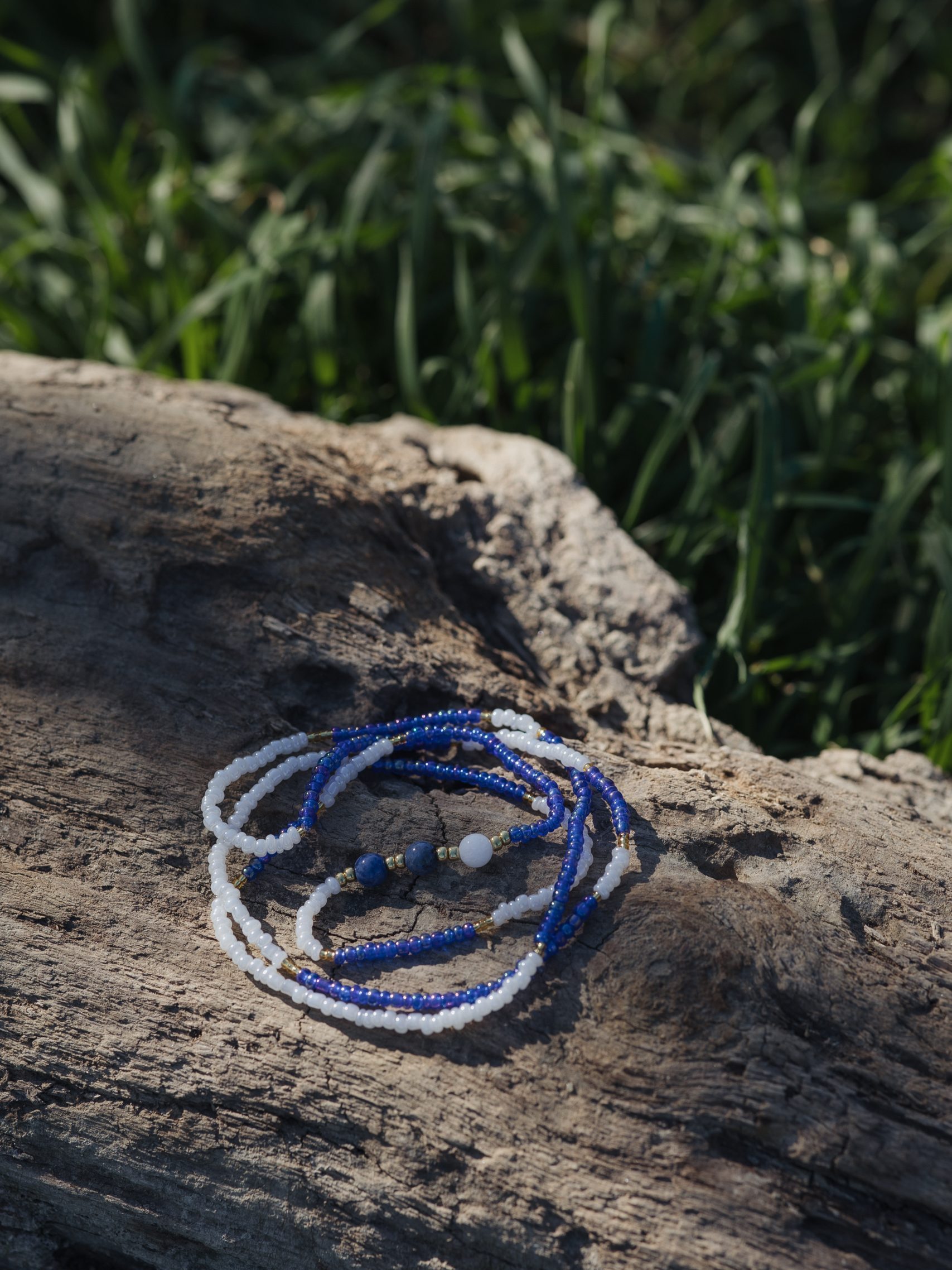 Baya bin bin élastique Soléia Tria en perles de verre bleu reflets violets lumineux éclatants nacré et perles de verre blanc blanches nacrées perles dorées japonaises miyuki pierres naturelles lapis lazuli sodalite et jade quartz blanc veritables fait main et sur mesure ajusté a la ma taille bijou de l'été à porter autour de la taille