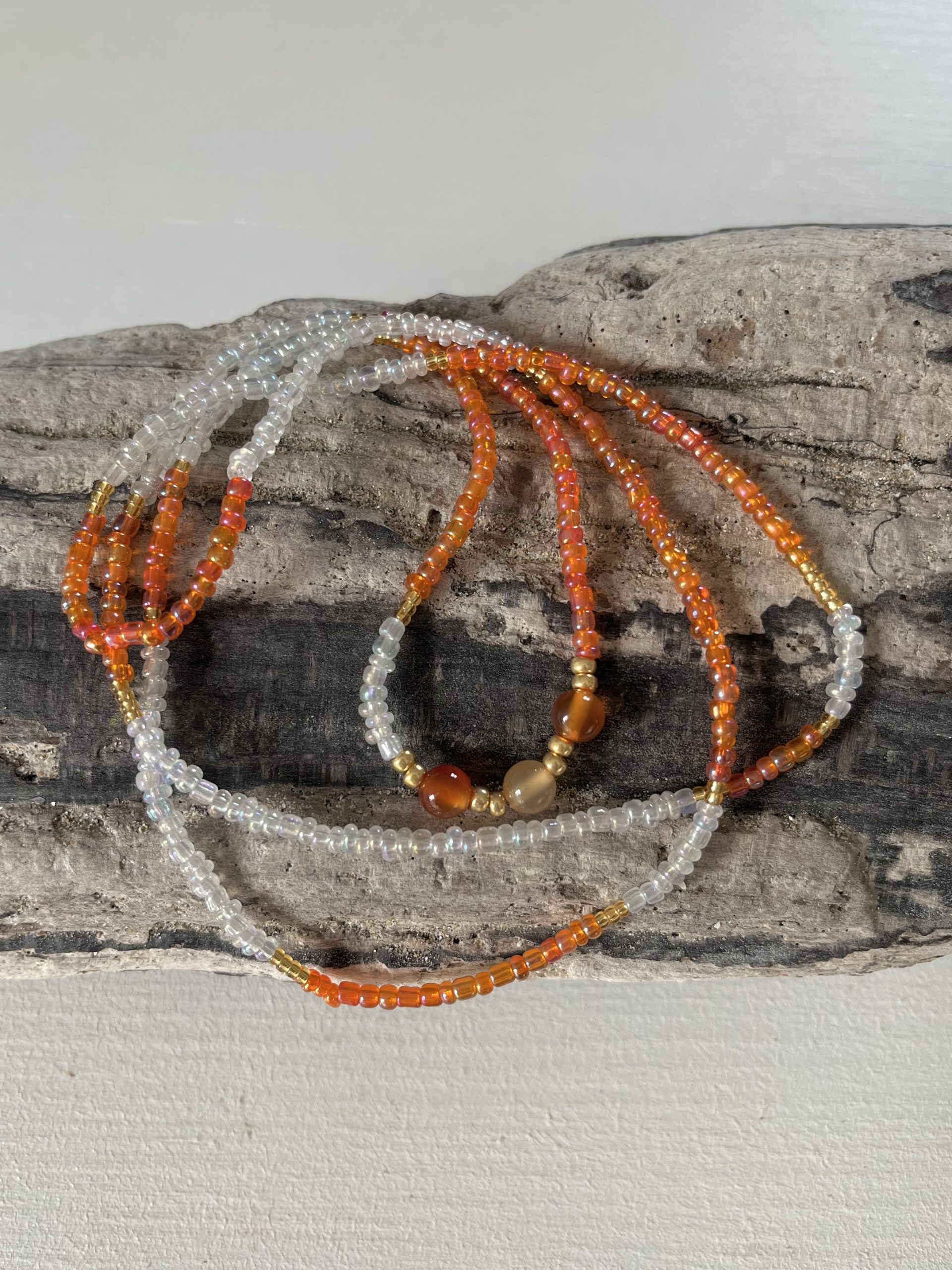 Baya bin bin élastique Soléia Tria en perles de verre orange vif reflets lumineux et perles transparentes cristal dorées japonaises miyuki et pierres naturelles agate cornaline veritables fait main et sur mesure ajusté a la ma taille bijou de l'été à porter autour de la taille