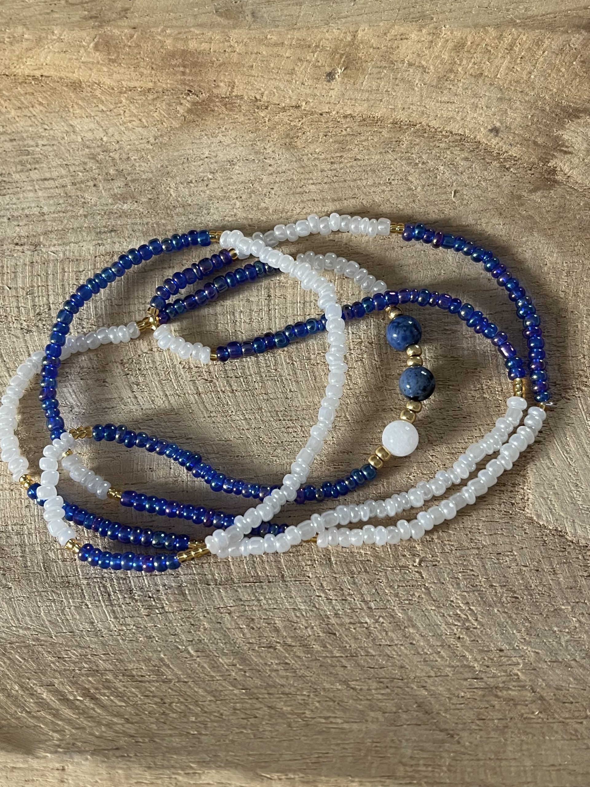 Baya bin bin élastique Soléia Tria en perles de verre bleu reflets violets lumineux éclatants nacré et perles de verre blanc blanches nacrées perles dorées japonaises miyuki pierres naturelles lapis lazuli sodalite et jade quartz blanc veritables fait main et sur mesure ajusté a la ma taille bijou de l'été à porter autour de la taille