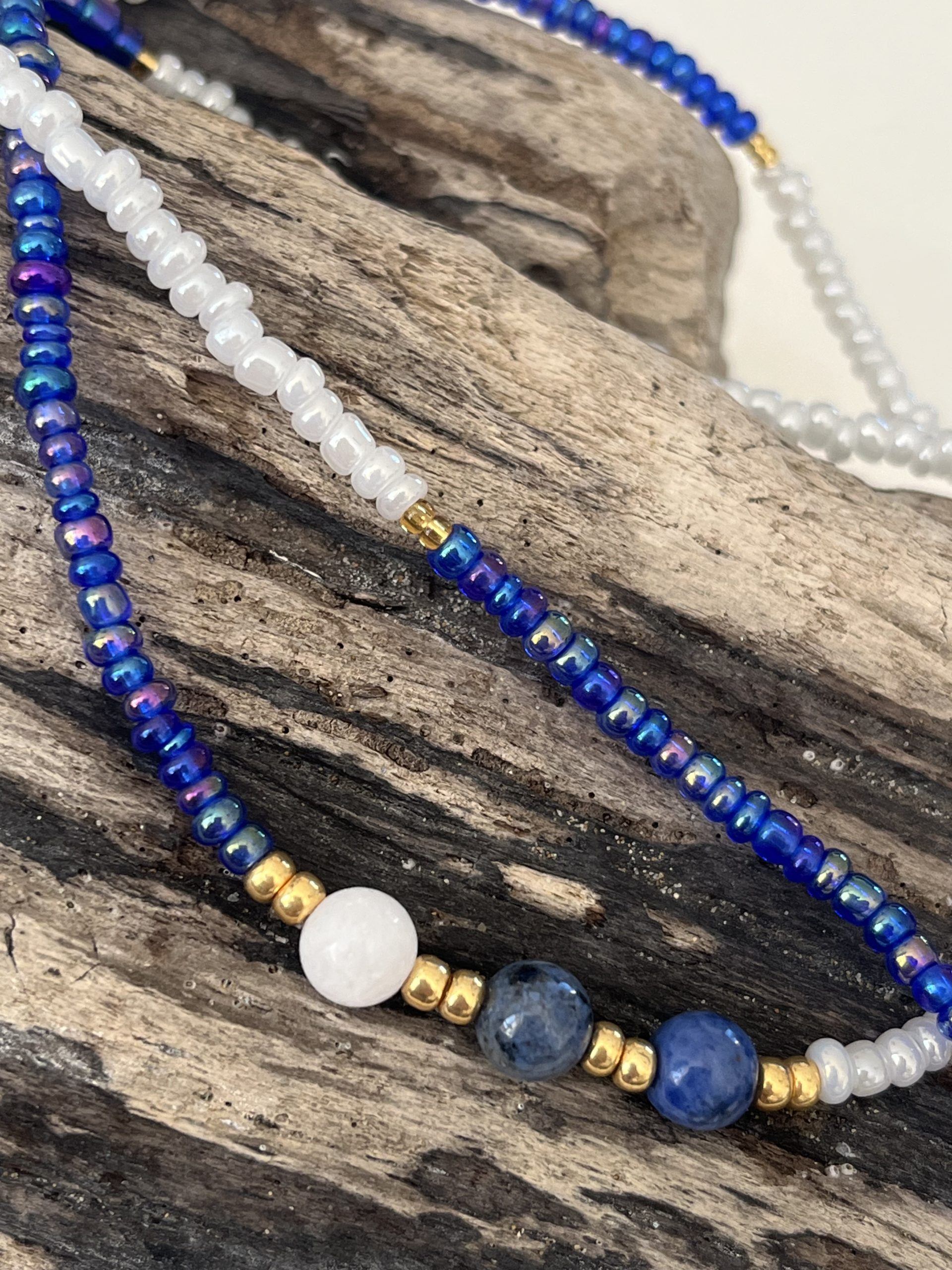 Baya bin bin élastique Soléia Tria en perles de verre bleu reflets violets lumineux éclatants nacré et perles de verre blanc blanches nacrées perles dorées japonaises miyuki pierres naturelles lapis lazuli sodalite et jade quartz blanc veritables fait main et sur mesure ajusté a la ma taille bijou de l'été à porter autour de la taille