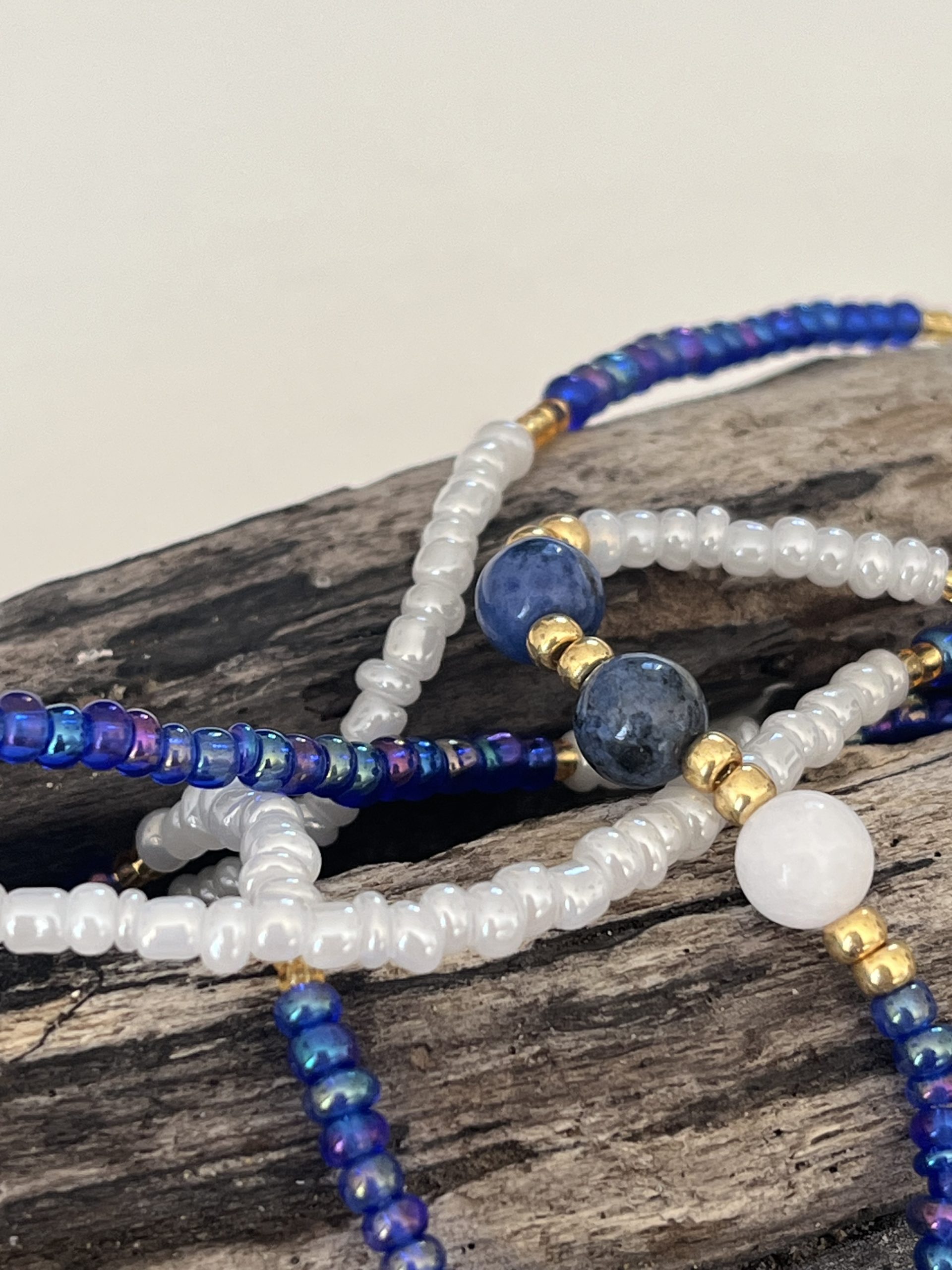 Baya bin bin élastique Soléia Tria en perles de verre bleu reflets violets lumineux éclatants nacré et perles de verre blanc blanches nacrées perles dorées japonaises miyuki pierres naturelles lapis lazuli sodalite et jade quartz blanc veritables fait main et sur mesure ajusté a la ma taille bijou de l'été à porter autour de la taille