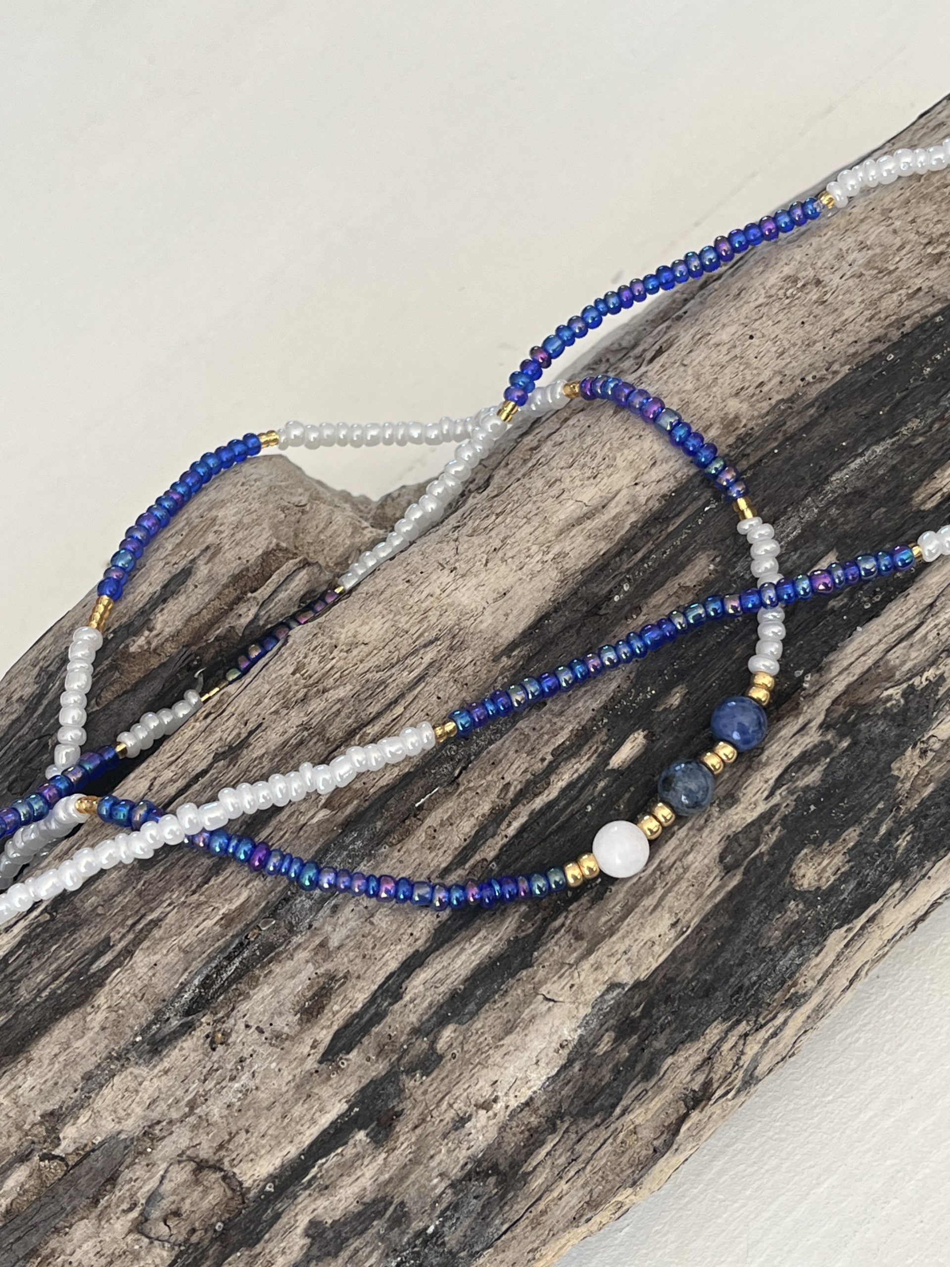 Baya bin bin élastique Soléia Tria en perles de verre bleu reflets violets lumineux éclatants nacré et perles de verre blanc blanches nacrées perles dorées japonaises miyuki pierres naturelles lapis lazuli sodalite et jade quartz blanc veritables fait main et sur mesure ajusté a la ma taille bijou de l'été à porter autour de la taille